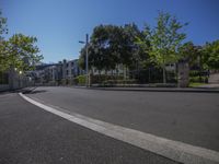 an empty street with trees in the middle of it and a fence surrounding the road