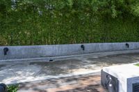 concrete boxes are placed in front of a green wall and a black metal planter