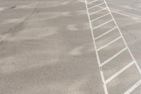 the man walks across the white lines of a parking lot for his vehicle to drive