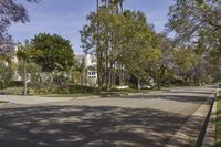 a view of the street in a suburban town with many trees lining the sidewalk and buildings