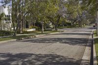 a view of the street in a suburban town with many trees lining the sidewalk and buildings