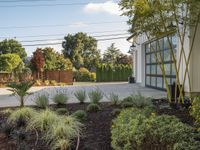 a driveway in front of a garage next to a tree and shrubbery area outside