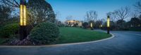 a lighted light is on near bushes and trees at night of the beautiful mansion's estate