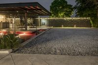 a gravel yard, with a stone walkway in front of it, leads to a modern glass front patio