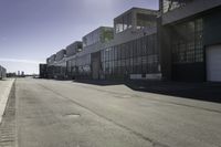 an empty industrial building with windows in the middle of it and an empty parking lot to the side