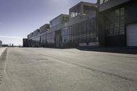 an empty industrial building with windows in the middle of it and an empty parking lot to the side