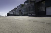 an empty industrial building with windows in the middle of it and an empty parking lot to the side