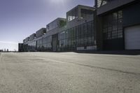 an empty industrial building with windows in the middle of it and an empty parking lot to the side