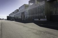 an empty industrial building with windows in the middle of it and an empty parking lot to the side