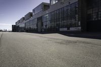 an empty industrial building with windows in the middle of it and an empty parking lot to the side