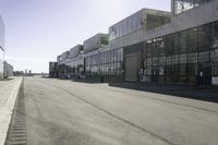 an empty industrial building with windows in the middle of it and an empty parking lot to the side