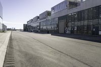 an empty industrial building with windows in the middle of it and an empty parking lot to the side