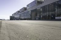 an empty industrial building with windows in the middle of it and an empty parking lot to the side