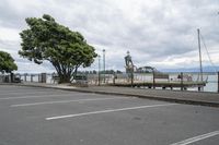 a person standing on a bench next to the water and pier near trees and a fence