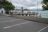 a person standing on a bench next to the water and pier near trees and a fence