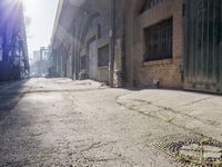 a street with concrete sidewalk and brick building with the sun in background and light reflecting through the window