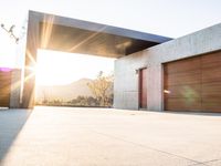 the sun shines over a garage door in a building near some mountains of green