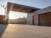 the sun shines over a garage door in a building near some mountains of green