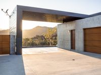 the sun shines over a garage door in a building near some mountains of green