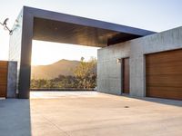 the sun shines over a garage door in a building near some mountains of green