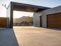 the sun shines over a garage door in a building near some mountains of green