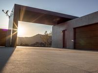 the sun shines over a garage door in a building near some mountains of green