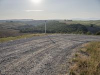 an empty road in front of a hill and a road pole on one side of the picture