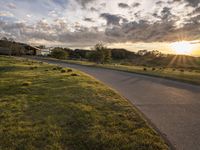 a picture of the sun shining down on some grass and houses by the road on the other side