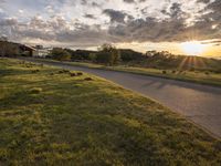 a picture of the sun shining down on some grass and houses by the road on the other side