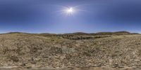 a fish eye view of a landscape in the sunlight with hills and a body of water