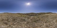 a fish eye view of a landscape in the sunlight with hills and a body of water