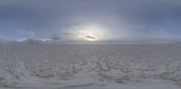 the sun is peeking through a cloudy sky over some sand dunes with the ocean on one side