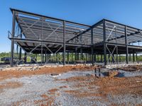 a picture of a building being built on a field near a forest in the background