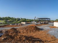 a picture of a building being built on a field near a forest in the background