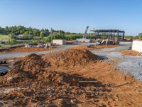 a picture of a building being built on a field near a forest in the background