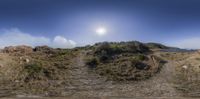 the sunny sun shines over the hillside by the water and sand shore near an ocean