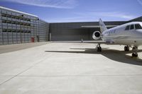 an airplane is sitting on the tarmac at a hangar as people watch from it