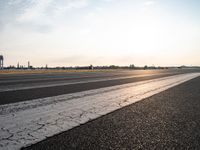 the sun is shining on the runway of an airport as traffic passes by in the distance