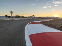 a photo of a dirt race track with sun setting in the distance of the track