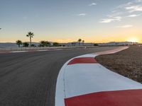 a photo of a dirt race track with sun setting in the distance of the track