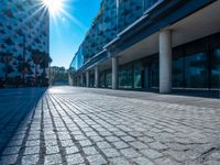 the sun is shining over a modern building near a street with trees and concrete slabs