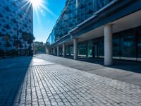 the sun is shining over a modern building near a street with trees and concrete slabs