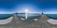 a 360 - angle view of the beach with buildings in the background and a sun glaring on the water