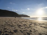 a sandy beach with footprints and waves on a sunny day at the ocean's edge