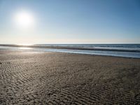 the sun shines brightly in front of a calm ocean at this beach scene of sand and water