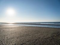 the sun shines brightly in front of a calm ocean at this beach scene of sand and water