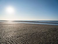 the sun shines brightly in front of a calm ocean at this beach scene of sand and water