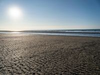 the sun shines brightly in front of a calm ocean at this beach scene of sand and water