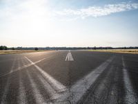 an air strip that is next to an open field in a country side lot with a few clouds