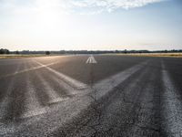 an air strip that is next to an open field in a country side lot with a few clouds